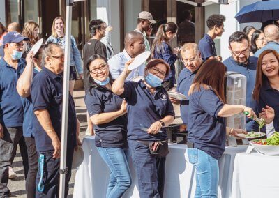 A group of SHCS staff wearing navy blue SHCS shirts in line for food at the 2022 SHCS Staff Appreciation BBQ