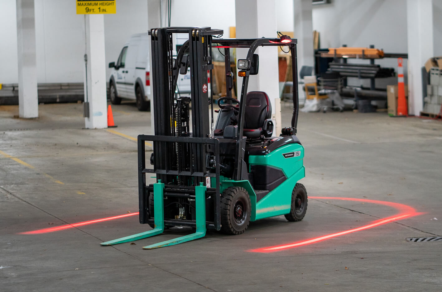 Green forklift in a warehouse surrounded by a horseshoe of red HALO light 